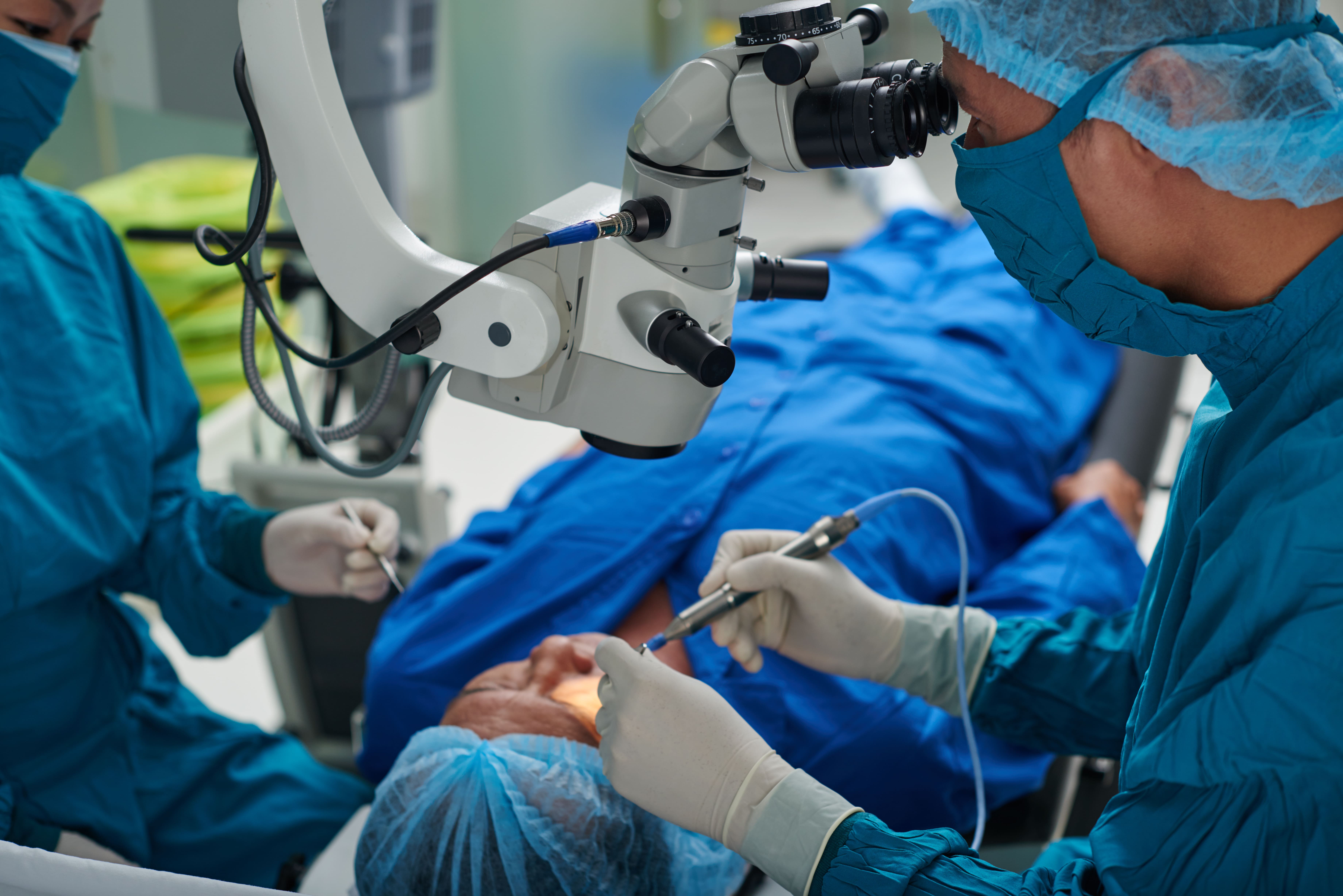 Retinal detachment surgery being performed by a Lumin Eye surgeon using a microscope in a modern operating theatre.