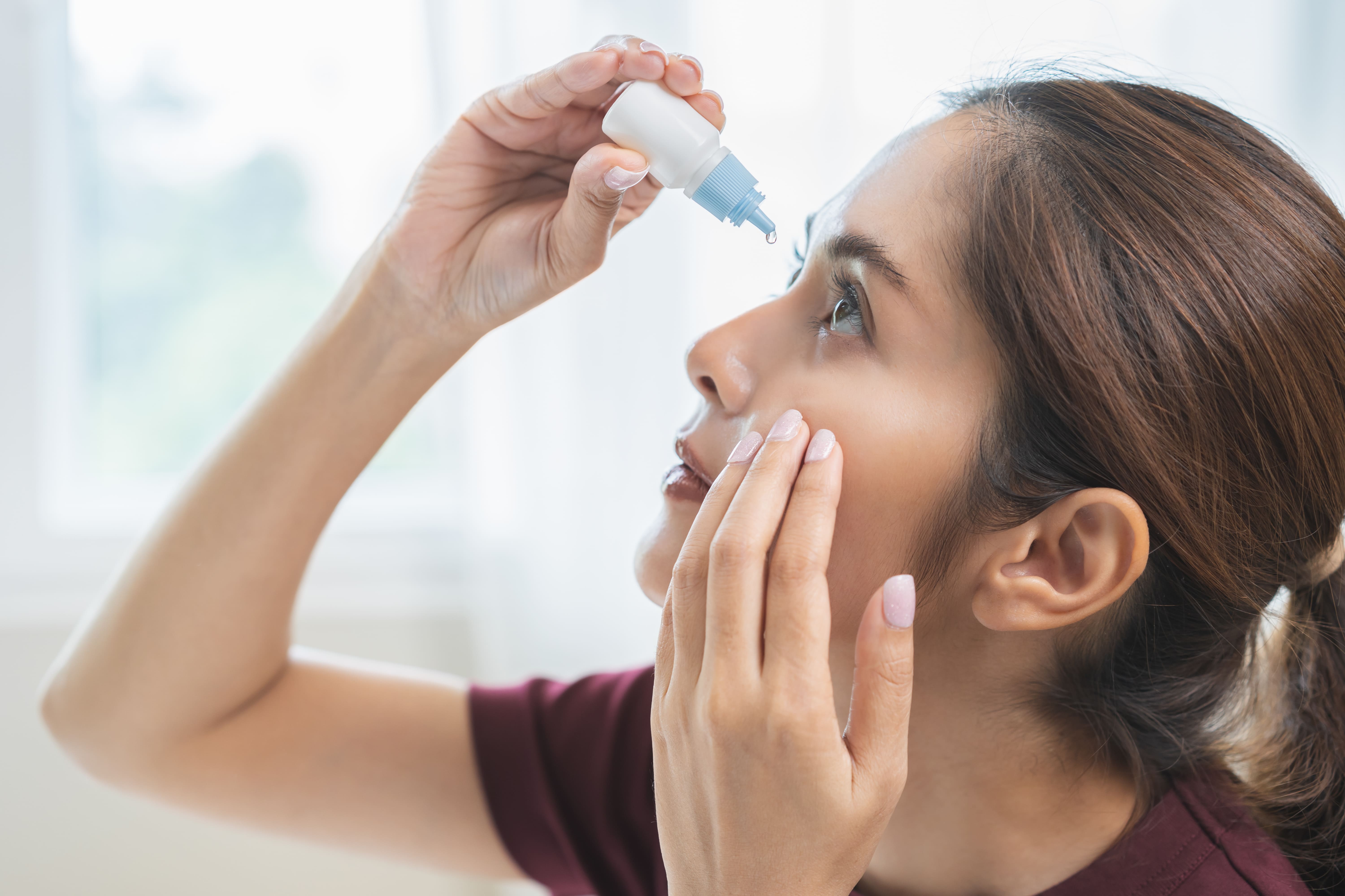 Woman applying eye drops for dry eyes, highlighting when to consult an eye specialist in Singapore for ongoing irritation.