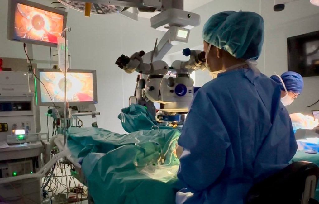 Retinal detachment surgery being performed by a Lumin Eye surgeon using a microscope in a modern operating theatre.
